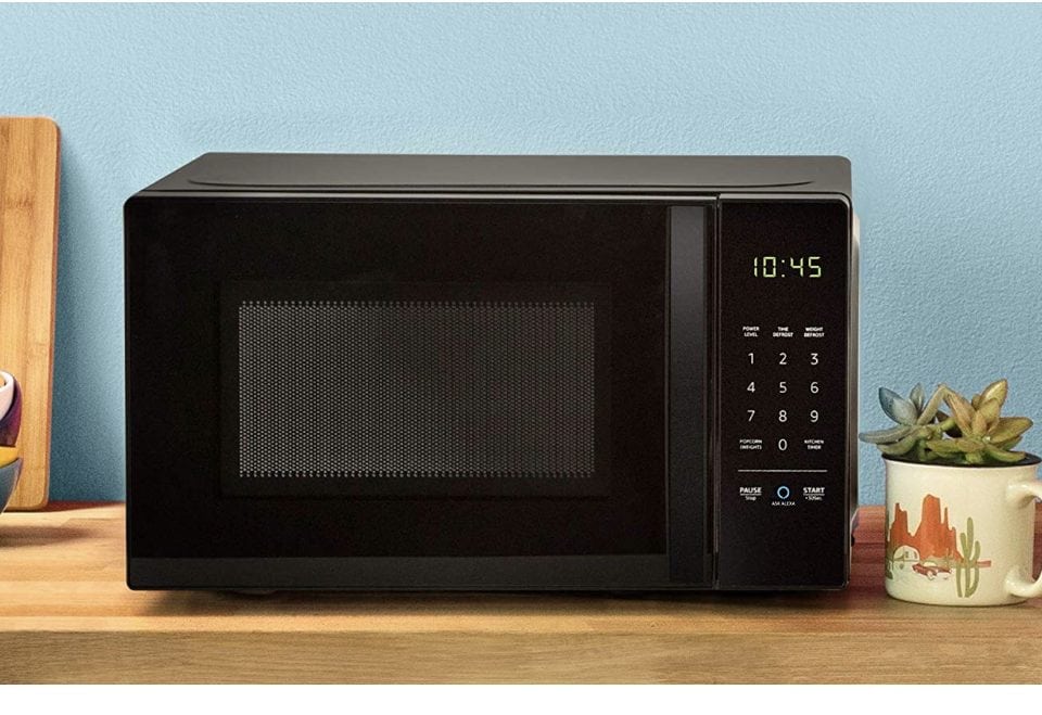 A screenshot of the Amazon Basic Microwave, it is black sitting on a wooden desktop