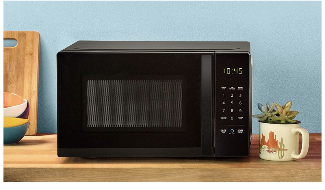 A screenshot of the Amazon Basic Microwave, it is black sitting on a wooden desktop